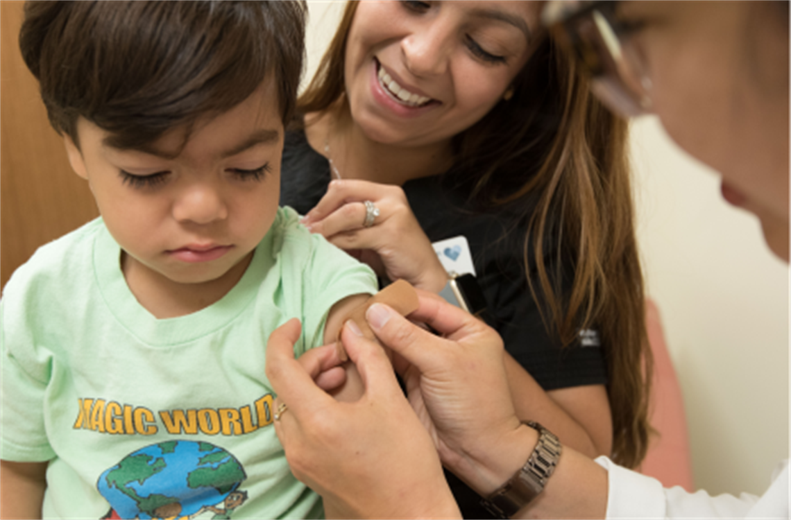 Vaccine Clinic photo of child getting vaccines with doctor and parent present.